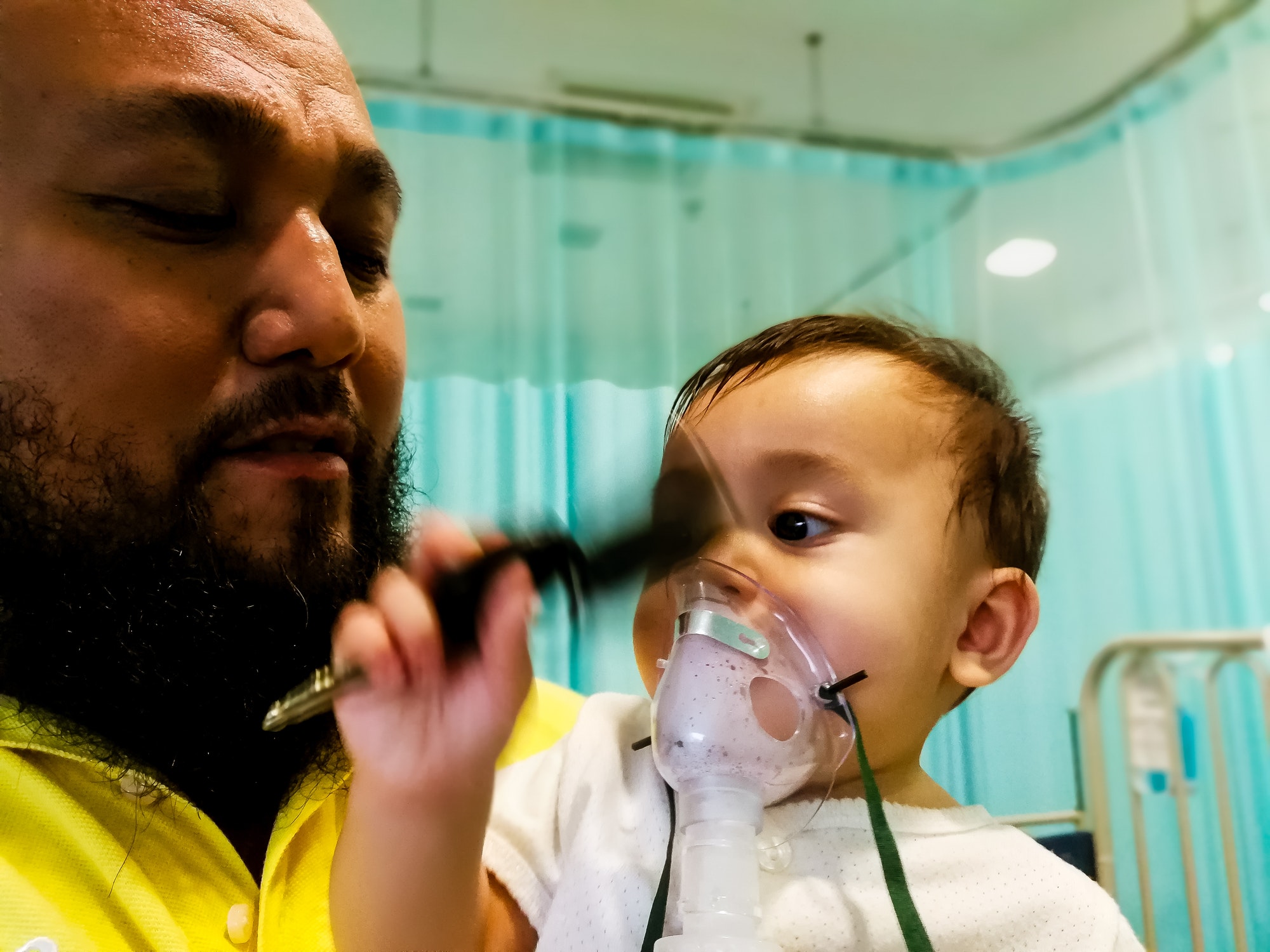 sick baby on inhaler carried by the father at the hospital