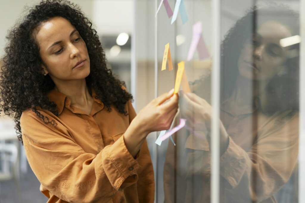 Businesswoman using sticky notes, agile methodology for productivity working in modern office