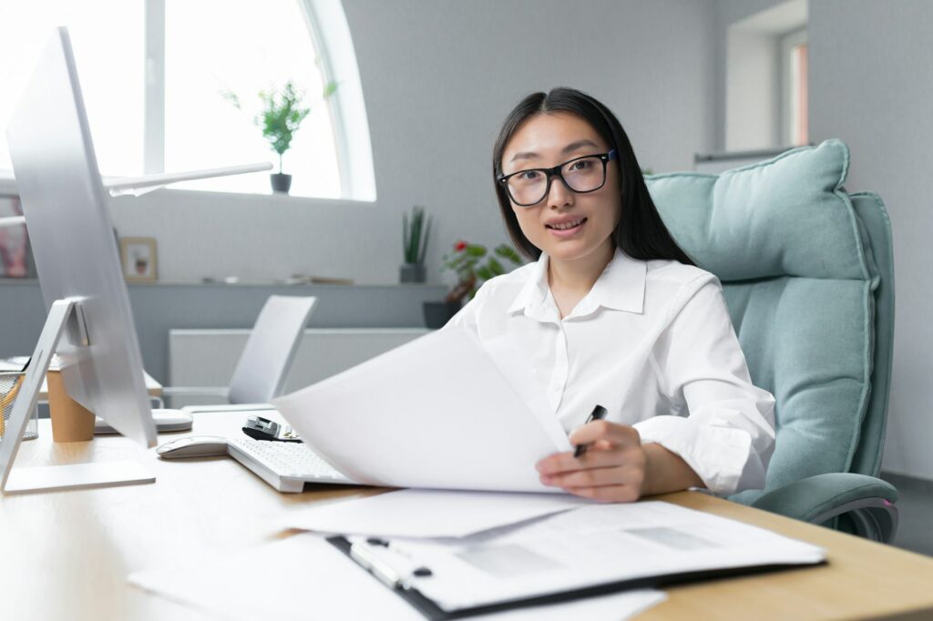 Portrait of young successful Asian financier, businesswoman working in office